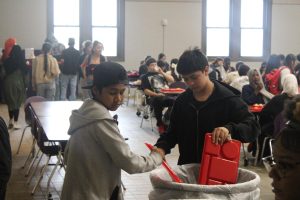 Students throw away lunches keeping the reusable trays and silverware. 